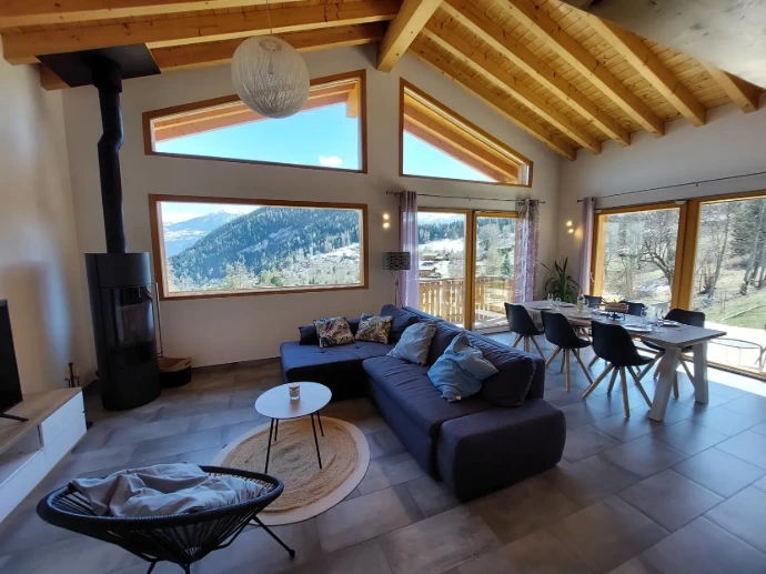 Séjour lumineux avec grande vitre et vue sur les montagnes